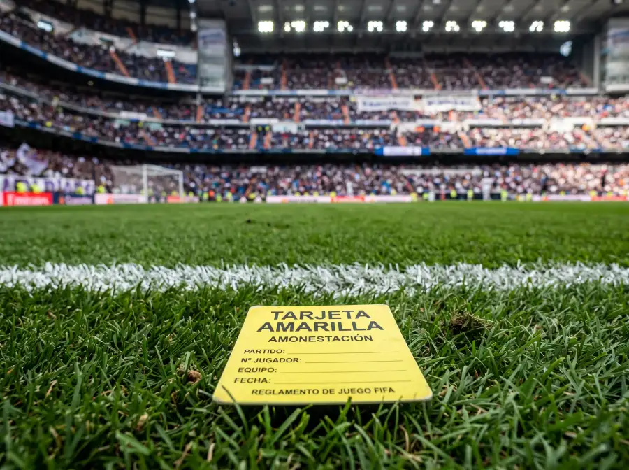 Tarjeta amarilla de fútbol sobre césped verde de un campo de fútbol profesional