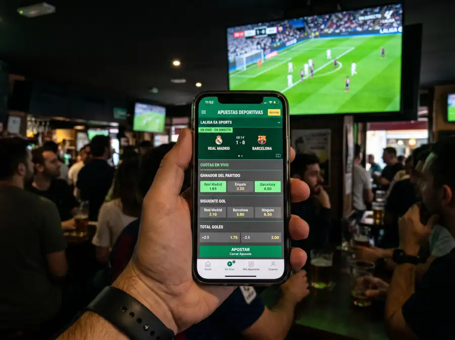 Pantalla de smartphone mostrando una interfaz de apuestas en vivo durante un partido de fútbol